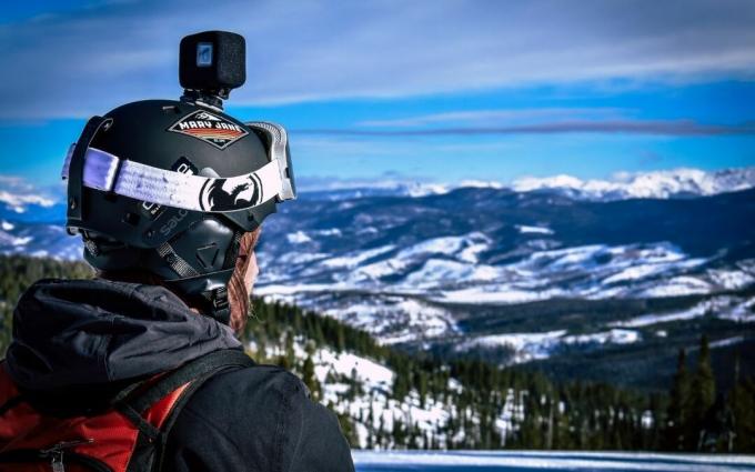 Mann im Helm mit Action-Kamera mit Blick auf Snow Mountain